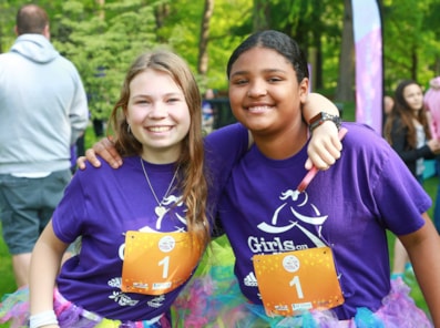 Two people wearing girls on the run shirts, smiling at the camera.